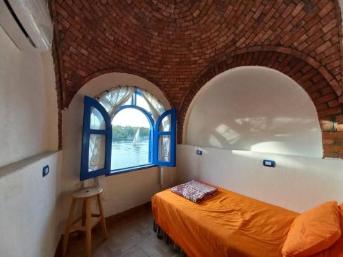 1 dormitorio con 2 ventanas arqueadas y 1 cama en Nubian Lotus en Asuán