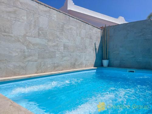 a swimming pool in front of a stone wall at Casa Nina in Vejer de la Frontera