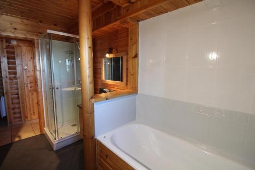 La salle de bains est pourvue d'une baignoire et d'une douche en verre. dans l'établissement Zénitude: Superbe chalet baigné de soleil, à Font-Romeu-Odeillo-Via