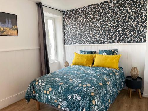 1 dormitorio con cama con colcha azul y almohadas amarillas en Les Jardins du Château, en Châteauroux