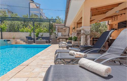 a row of chaise lounge chairs next to a swimming pool at Beautiful Home In Brodarica With Wifi in Brodarica