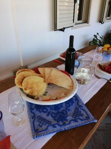 a table with a plate of bread and a bottle of wine at Appartamento Meduse in Cala Gonone