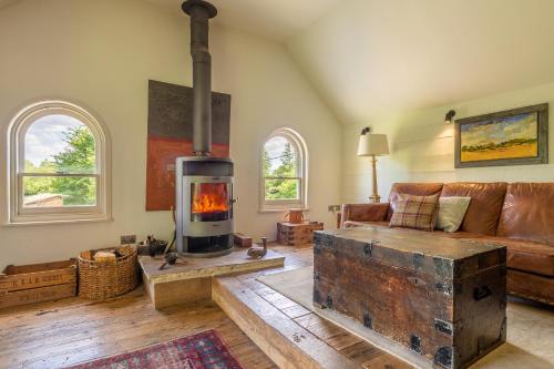 a living room with a couch and a wood stove at Heavenly luxury rustic cottage in historic country estate - Belchamp Hall Mill in Belchamp Otten