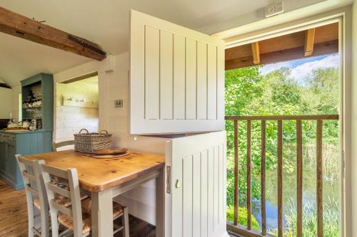 a kitchen with a table and a balcony at Heavenly luxury rustic cottage in historic country estate - Belchamp Hall Mill in Belchamp Otten