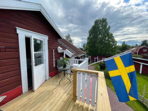 a deck with a red house with a flag on it at Prinsgården B&B rum stugor in Mora