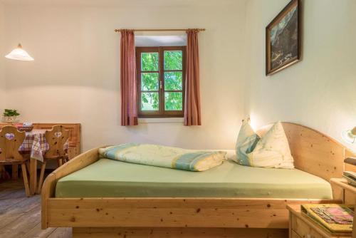 1 dormitorio con cama de madera y ventana en Sallrain Hof Monolokal 4, en Collalbo