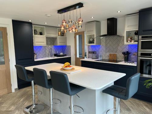 uma cozinha com uma mesa branca e armários azuis em Stylish Modern Home with Parking Enclosed Garden em Holyhead