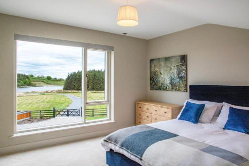 a bedroom with a bed and a large window at Ballymacooda House in Drumadrohid