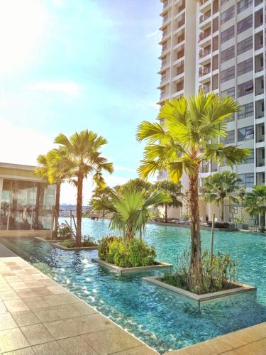 a swimming pool with palm trees in front of a building at Sara Staycation in Kajang