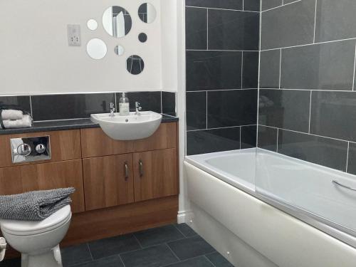 a bathroom with a toilet and a sink and a bath tub at 3 Mackay Road in Dornoch