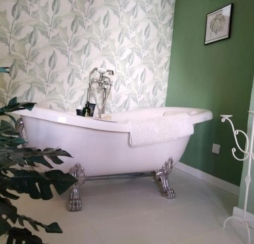 a bath tub in a bathroom with a green wall at CasaBoutique cerca del mar con vistas a la montaña in Polop