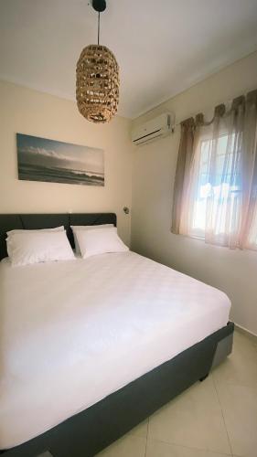 a bedroom with a large white bed and a chandelier at Elena apartment chalkidiki in Kallithea Halkidikis