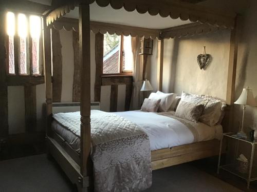 um quarto com uma cama de dossel com lençóis e almofadas brancos em Valley Farmhouse B&B em Southwold