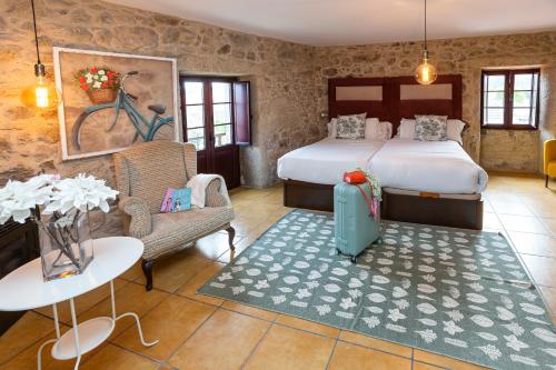a bedroom with a bed and a table with a suitcase at Ecocasa Lema II in Muxia