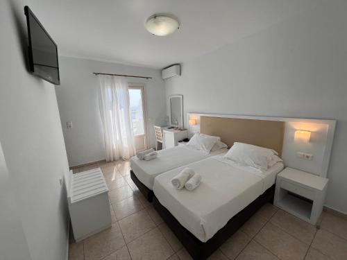 a bedroom with two beds with white sheets and towels at Smy Bellevue Mykonos in Tourlos