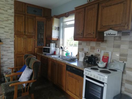 a kitchen with wooden cabinets and a white stove top oven at Rossport bungalow with an Atlantic view in Ballina