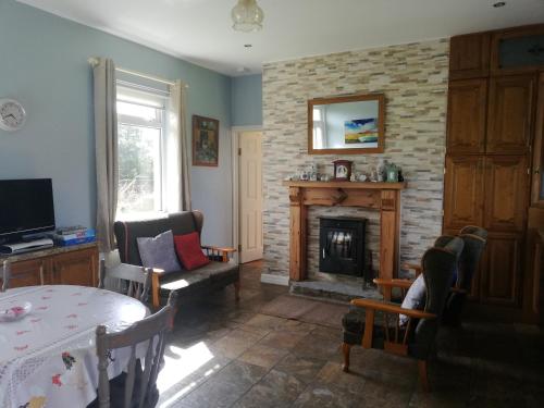 a living room with a table and a fireplace at Rossport bungalow with an Atlantic view in Ballina