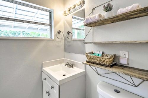 a bathroom with a sink and a toilet and a window at Merritt Island Oasis with Pool about 7 Mi to Beach! in Merritt Island