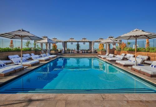 a swimming pool with lounge chairs and umbrellas at SIXTY Beverly Hills in Los Angeles