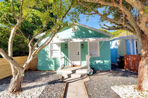 a green house with a porch and a tree at ModernTropic 2bd/1ba Near Beach w/ fence yard/deck in Lake Worth
