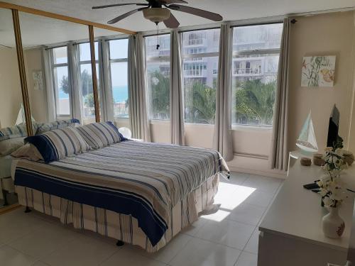 a bedroom with a bed with windows and a ceiling fan at Coral Beach Isla Verde Beach Front Large 1 Bedroom Apt 208 Tower 1 in San Juan
