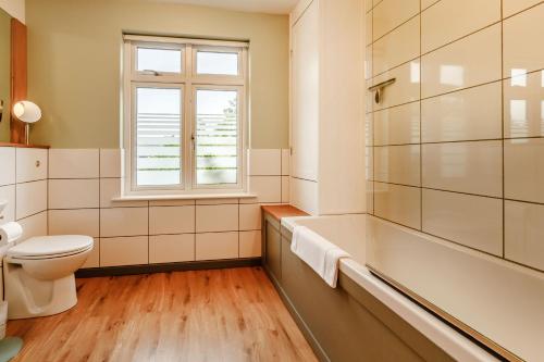ein Badezimmer mit Badewanne und Toilette und einem Fenster in der Unterkunft 11 Beech Road in Weymouth