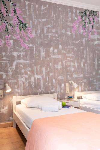a bedroom with two beds and a wall with flowers at Dimitra's Garden - Holiday Apartments in Parga