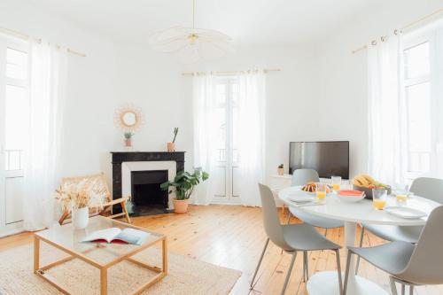 una sala de estar blanca con mesa y sillas en Coachella Vintage Chic in the Heart of St Charles Biarritz, en Biarritz