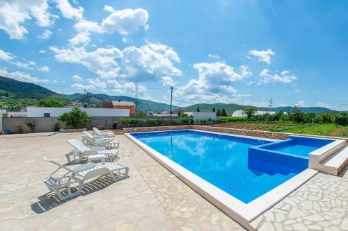 a swimming pool with chaise lounge chairs and a pool at Villa ATL in Blagaj