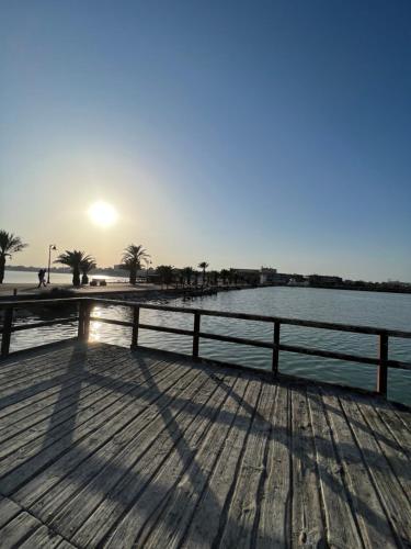 a pier with the sun setting over a body of water at Apartamentos Sol y Lodo in Lo Pagán