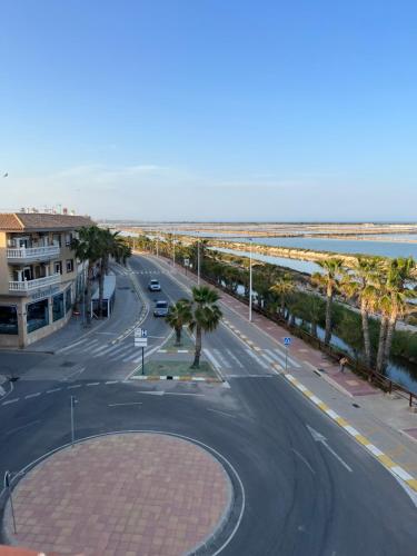 an empty street with palm trees and the ocean at Apartamentos Sol y Lodo in Lo Pagán