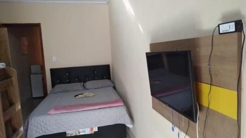 Schlafzimmer mit einem Bett und einem Flachbild-TV in der Unterkunft Dom Antonio 3 in Campos dos Goytacazes