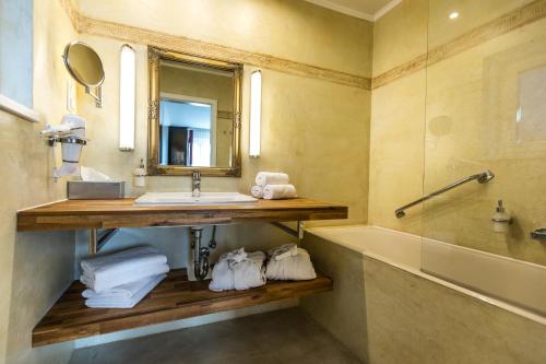a bathroom with a sink and a tub and a mirror at Landidyll-Hotel Nudelbacher in Feldkirchen in Kärnten