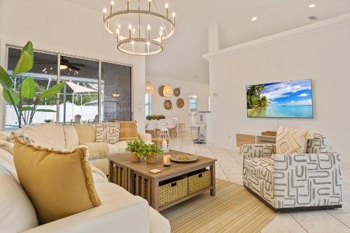 a living room with white furniture and a chandelier at VILLA LAS PALMAS Beautiful Fenced-in Pool Home with Spa- Sleeps 8 in Flagler Beach
