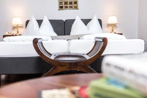 a chair in front of a bed with white pillows at Landidyll-Hotel Nudelbacher in Feldkirchen in Kärnten