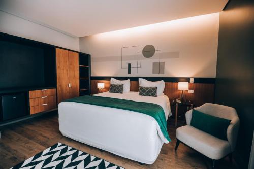 a bedroom with a large white bed and a chair at Villa Amistà Campos do Jordão in Campos do Jordão