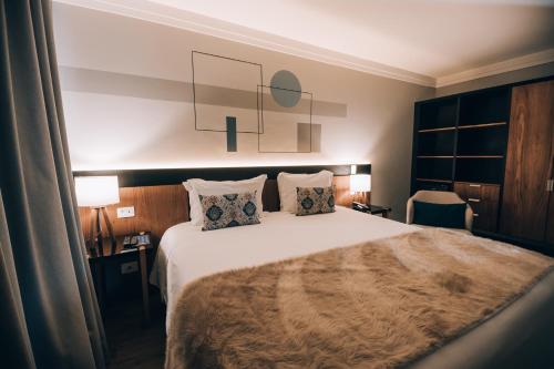 a bedroom with a large bed with two pillows at Villa Amistà Campos do Jordão in Campos do Jordão
