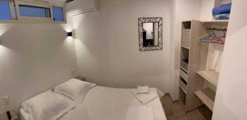 a small white bedroom with a bed and a mirror at Farfalla in Calvi