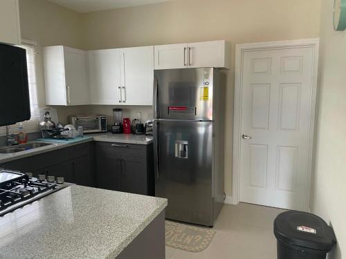 a kitchen with a stainless steel refrigerator and white cabinets at Aquamarine Resort-style Vacations in Lucea