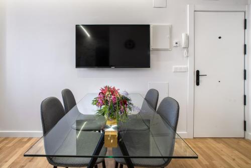 a dining room table with chairs and a television on a wall at Apartamentos La Jasa in Arguedas