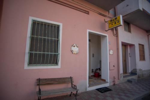 a pink building with a bench next to a window at B&B Cardedu in Cardedu