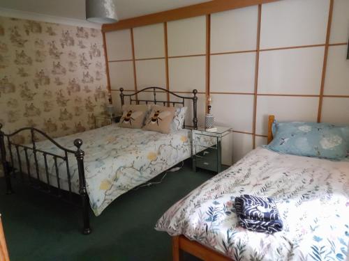 Grovewood House Retreat في Kirkbean: غرفة نوم بسريرين وموقف ليلي مع مفارش نوم