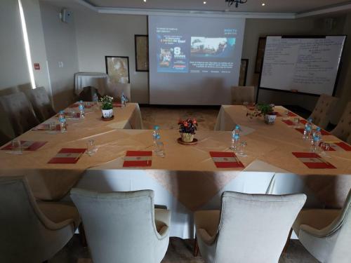 a conference room with a table and chairs and a screen at Hotel Medina Del Lago in Otavalo