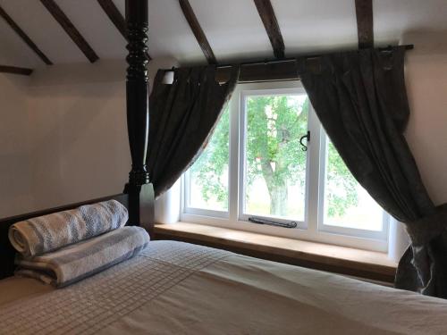 a bedroom with a bed and a large window at Village period cottage in Wolston
