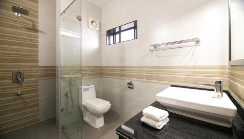 a bathroom with a toilet and a sink and a shower at Aloha Holiday Resort in Baga