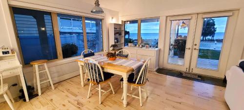 a kitchen with a table and chairs and windows at The White House in Sechelt