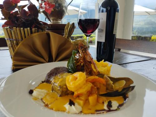 a plate of food on a table with a glass of wine at Hotel Medina Del Lago in Otavalo