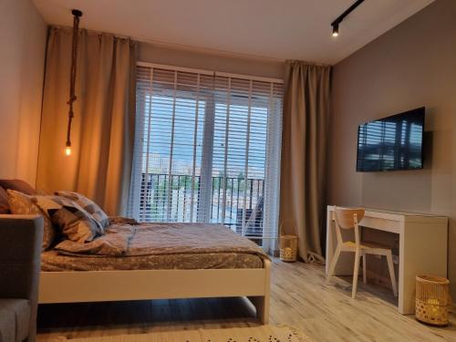 um quarto com uma cama, uma secretária e uma janela em Apple Apartments - Gdańska PRYWATNE MIEJSCE PARKINGOWE em Lódź