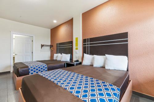a hotel room with two beds and orange walls at Lighthouse Inn in South Padre Island