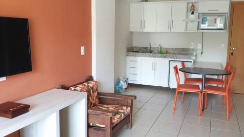 a kitchen and living room with a table and chairs at Águas da Serra Apart Service - acesso ao rio e vista pra serra in Rio Quente